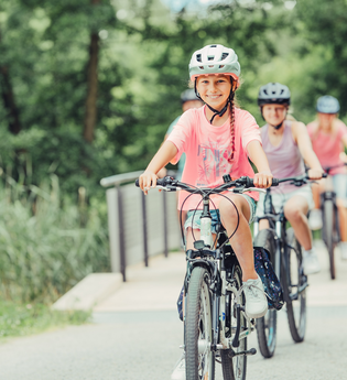 Ein großes und ein kleines Mädchen fahren Fahrrad. Im Hintergrund sind zwei weitere Menschen auf dem Fahrrad zu sehen. | © Touristikgemeinschaft HeilbronnerLand