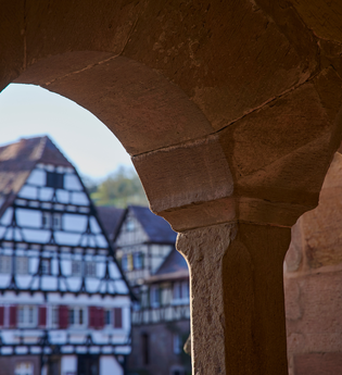Fachwerkgebäude im Klosterhof Maulbronn durch einen steinernen Fensterbogen betrachtet | © Kraichgau-Stromberg Tourismus e.V.