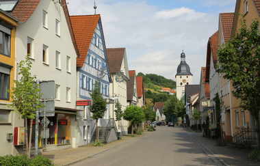 Entlang der Straße reihen sich Häuser und eine Kirche ist am Ende. | © Touristikgemeinschaft Hohenlohe e. V. | Andi Schmid