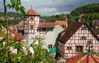 Blick auf das im Fachwerkstil errichtete Romschlössle. Im Vordergrund sind Rosen des dazugehörigen Rosengartens zu sehen. | © Tourist-Information Creglingen
