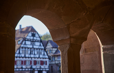 Fachwerkgebäude im Klosterhof Maulbronn durch einen steinernen Fensterbogen betrachtet | © Kraichgau-Stromberg Tourismus e.V.