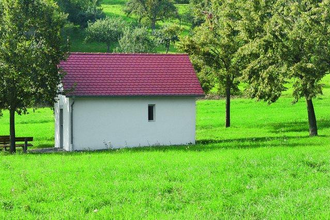 Die Kapelle liegt idyllisch inmitten einer grünen Wiese und Bäumen | © Touristikgemeinschaft Hohenlohe e. V. | Stadt Krautheim