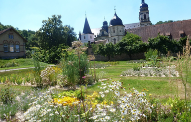 Im Garten blühen Arzneipflanzen und man kann auf das Kloster schauen | © Touristikgemeinschaft Hohenlohe e. V. | Hohenloher Gartenparadies