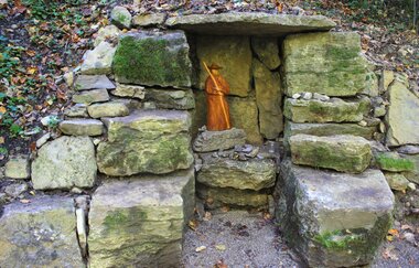 In einer Steinnische steht eine Figur von einem Pilger. | © Touristikgemeinschaft Hohenlohe e. V.