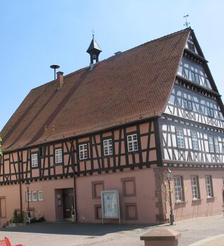 Rötliches Fachwerkgebäude an einer Straße | © Stadt Sinsheim