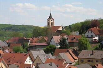 Blick auf eine Kirche auf einer Anhöhe und Häuserdächer | © Stadt Sinsheim