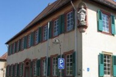 Historisches Gebäude mit weißen Sprossenfenstern und grünen Fensterläden an einem klaren Sommertag | © Stadt Sinsheim