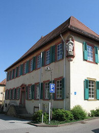 Historisches Gebäude mit weißen Sprossenfenstern und grünen Fensterläden an einem klaren Sommertag | © Stadt Sinsheim