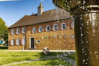 Wasserschloss Großeicholzheim mit Wiese und plätscherndem Brunnen im Vordergrund | © Touristikgemeinschaft Odenwald e.V.