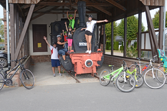 Gruppe aus Menschen posiert auf einer alten Dampflok. Vor der Dampflok befinden sich die Fahrräder der Gruppe | © Touristikgemeinschaft Odenwald e.V.