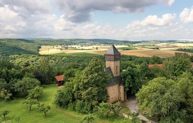 Blick auf den Ottilienberg mit einer historischen Burg  in grüner Landschaft.