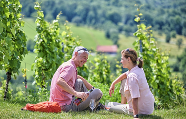 Zwei Wandernde im Weinberg mit Wein | © Touristikgemeinschaft Hohenlohe e. V. | Florian Trykowski
