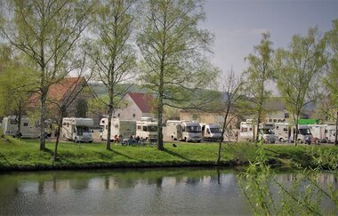 Blick auf den direkt an der Tauber gelegenen Wohnmobilstellplatz in Röttingen. Der Platz ist gut besucht. Im Hintergrund sind Häuser zu sehen. | © Tourist-Information Röttingen