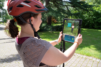 Frau die ein Tablet hält und die Augmented Reality App Weitersehen nutzt