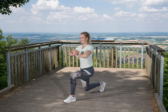 Eine Sportlerin macht eine Kniebeuge auf einer Aussichtsplattform | © Touristikgemeinschaft Hohenlohe e. V. | Fa. Würth.