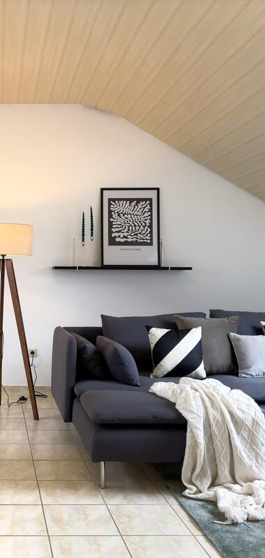 Stilvoll eingerichteter Raum mit blauem Sofa, einem großen Esstisch und diversen Dekoelementen | © FeWo Bäuerle & Schmid
