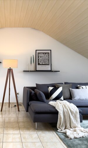 Stilvoll eingerichteter Raum mit blauem Sofa, einem großen Esstisch und diversen Dekoelementen | © FeWo Bäuerle & Schmid