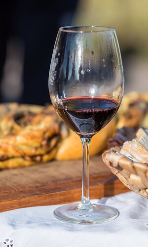 Glas Rotwein, Korb mit Brot und Brett mit Hefezopf | © Dieter Anzock