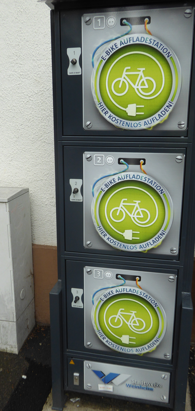Ladestation mit grünem runden Schild, das ein Fahrrad und ein Steckersymbol zeigt, mit Text 'E-Bike Aufladestation Hier kostenlos aufladen!'. | © Landratsamt Rhein-Neckar-Kreis, Foto Beate Otto